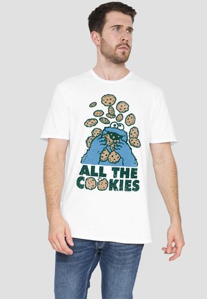White cotton t-shirt featuring a blue cartoon character grabbing cookies, with "ALL THE COOKIES" text in a bold, distressed green font.