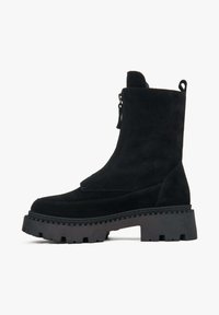 Zwarte suède enkelboot met een stevige rubberen zool, voorzien van een zijrits en een trekband, ontworpen voor een veilige pasvorm en gemakkelijke instap.