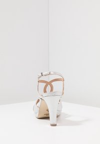 Zilveren hoge hakken sandalen met een enkelbandje, soepele glinsterende textuur, open achterkant en een gemiddelde hakhoogte.