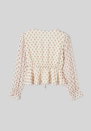 Blouse de couleur crème à motif floral, manches longues, taille cintrée et ourlet à volant. Le matériau semble léger et texturé.