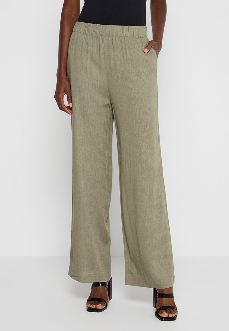 Weite Beinhosen in Olivgrün, aus einem strukturierten Gewebe gefertigt. Mit einem elastischen Taillenbund und seitlichen Taschen. Tragen Sie sie mit schwarzen Sandalen.