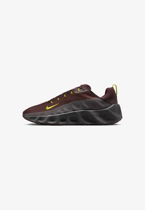 Chaussure de sport marron foncé avec semelle noire épaisse et texturée, swoosh Nike jaune, œillets pour les lacets et languette de maintien au talon sur fond blanc.
