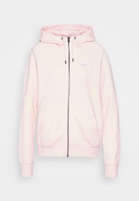 Rosa zip-up hoodie gjort av mjukt tyg, med en känguruficka, dragsko i huvan och en liten vit Nike-logotyp på bröstet.