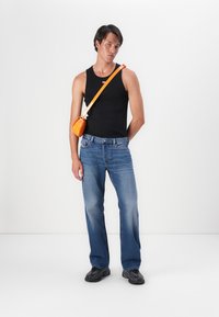 Zwart tanktop, blauwe denim jeans en zwarte sneakers. Oranje schoudertas en gladde texturen. Slim fit, casual ontwerp met minimale details.