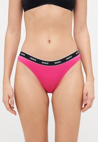 Rosa bomulls-bikiniunderdelar med svart elastisk midjeband med hvit tekst. Designet har en klassisk trekantform.