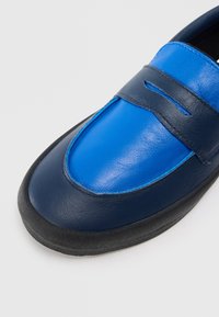 Modré a tmavě modré kožené boty s hladkým povrchem, kulatou špičkou a černou gumovou podrážkou s minimalistickým designem a našitými detaily.