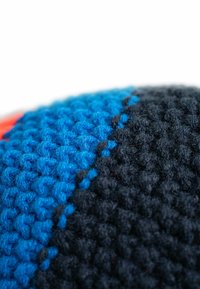Textured textile featuring a blue and black pattern, with distinct stitching. The surface is soft, made from woven fibers.