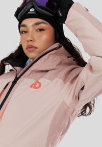 Lyserød og grå skijakke med scuba-hette, lynlås-lommer og logo på brystet; har tekstureret stof og justerbare manchetter.