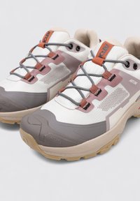 Calzado con parte superior de malla blanca y acentos en gris y rosa, suela acolchada y cordones grises. Diseñado para comodidad y durabilidad.