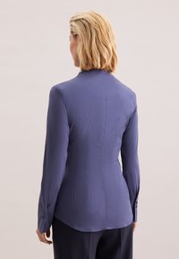 Op maat gemaakt overhemd met lange mouwen van gedempt blauw materiaal, met een aansluitend silhouet, subtiel verticaal naaddetail en knoopmanchetten.