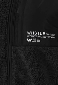 Musta takki fleece-pinnalla ja sileällä paneelilla. Siinä on valkoiset brändäykset: "WHSTLR / OUTDOOR" sekä ikonit hengittävyydestä ja lämmöstä.