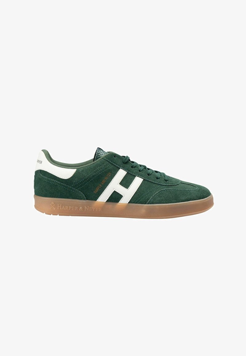 Zapatilla de ante verde con acentos blancos, que presenta una suela plana de goma y detalles perforados en la lengüeta. Marca en el lateral y en el talón.