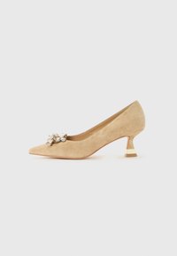 Beige suede kitten heel pump with pointed toe and decorative crystal embellishment on front.