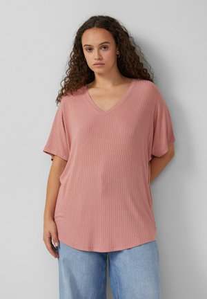 Haut rose en V côtelé à manches courtes, avec une coupe ample et un ourlet arrondi, associé à un jean large bleu clair.