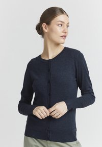 Cardigan bleu marine en tissu tricoté doux, avec un col rond, des manches longues et une fermeture à boutons sur le devant. Accents côtelés subtils.