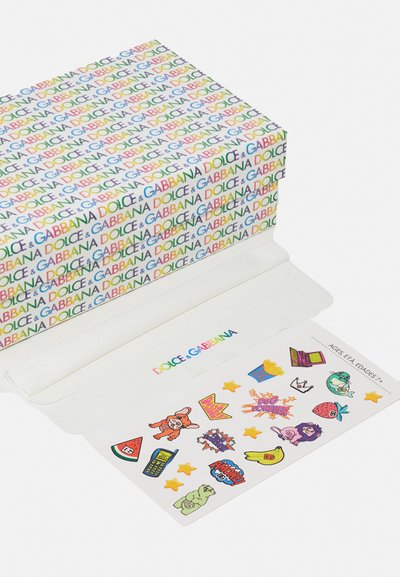 Supakuota dėžutė turi spalvingą pakartotinį „Dolce & Gabbana“ logotipą. Viduje yra įvairūs iliustruoti lipdukai ant balto fono.