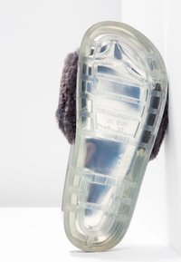 Genomskinlig plastisol med texturerat greppmönster, toppad med grått fluffigt övre material, designad för komfort och värme i fotwear.