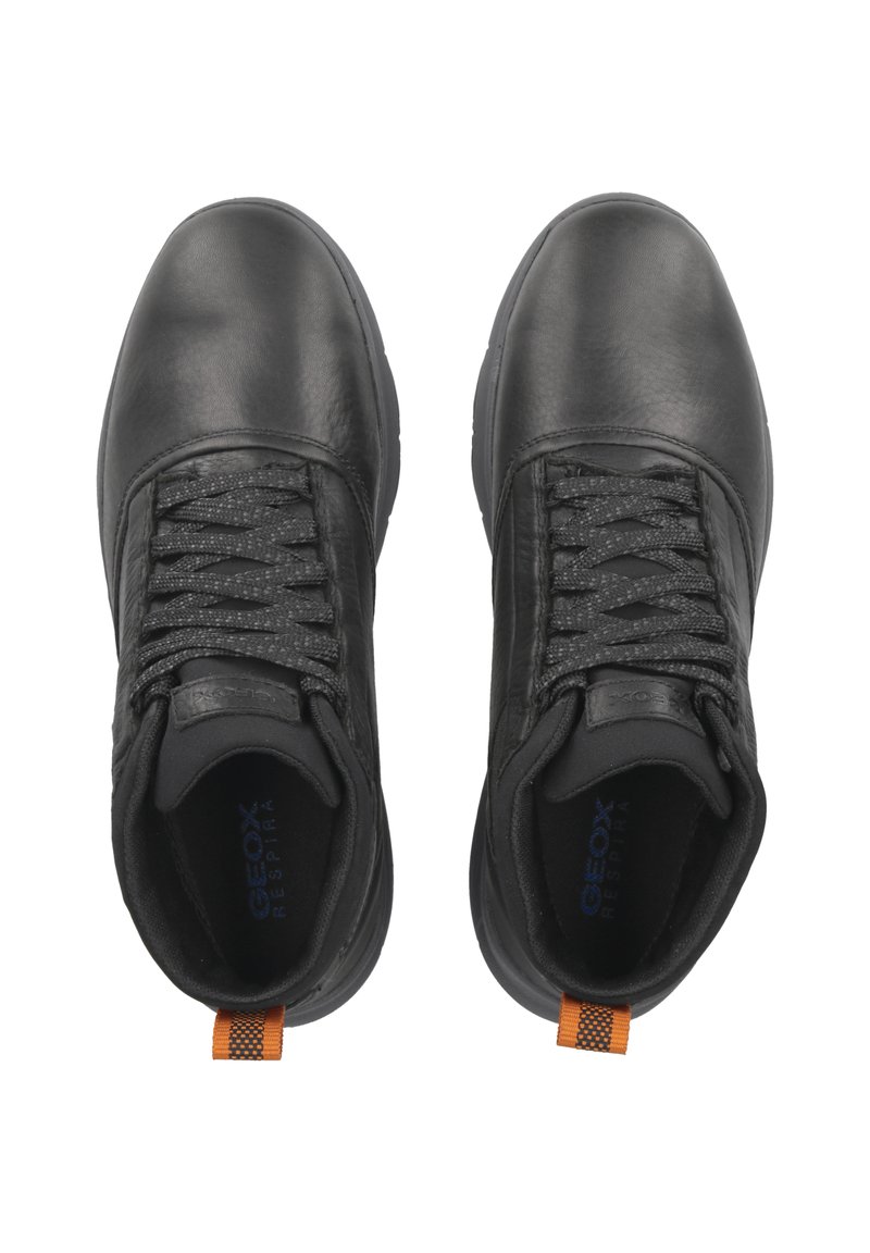 Scarpe in pelle nera con una tomaia testurizzata e lacci piatti. Una linguetta arancione a contrasto sul tallone aggiunge un tocco di design.