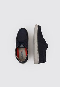 Chaussures en daim bleu marine avec un bout rond, un laçage, et une semelle en caoutchouc contrastante de couleur claire. L'intérieur comprend une semelle intérieure de marque.