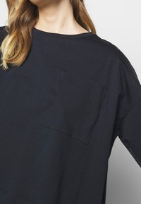 Übergroßes, navyblaues Baumwoll-T-Shirt mit Rundhalsausschnitt und einer Brusttasche. Mit entspannten Ärmeln und einer glatten Textur.