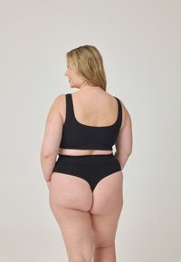 Czarny komplet bielizny z mieszanki bawełny, składający się z biustonosza bralette i majtek, charakteryzujący się gładką teksturą, szerokimi ramiączkami oraz wysokim wycięciem na nogi, pokazany od tyłu.