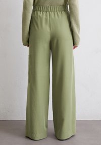 Lichtgroene, wijde broek met elastische tailleband en zijzak. Glad, lichtgewicht stof met minimale naden.