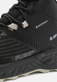 Schwarzer wasserdichter Wanderschuh mit einem strukturierten Mesh-Obermaterial, grauen Akzenten und einer robusten Sohle mit einem geometrischen Profil.