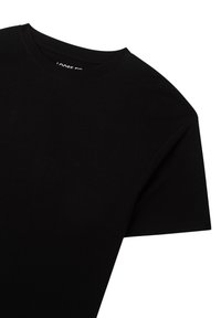 T-shirt nera a vestibilità ampia realizzata in cotone. Presenta un classico scollo rotondo e maniche corte. Texture liscia e senza motivo visibile.