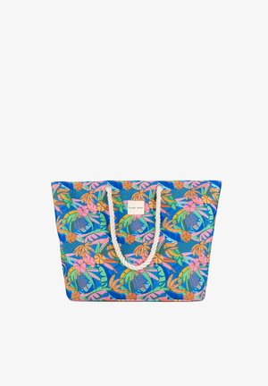 Bolso tote con estampado multicolor de hojas tropicales y flores, con asas gruesas de cuerda blanca y una pequeña etiqueta central.