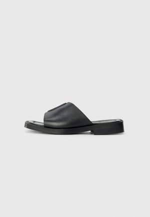 Sorte læder slide sandaler med en glat tekstur, åben tå, bred rem-design og en flad gummisål.