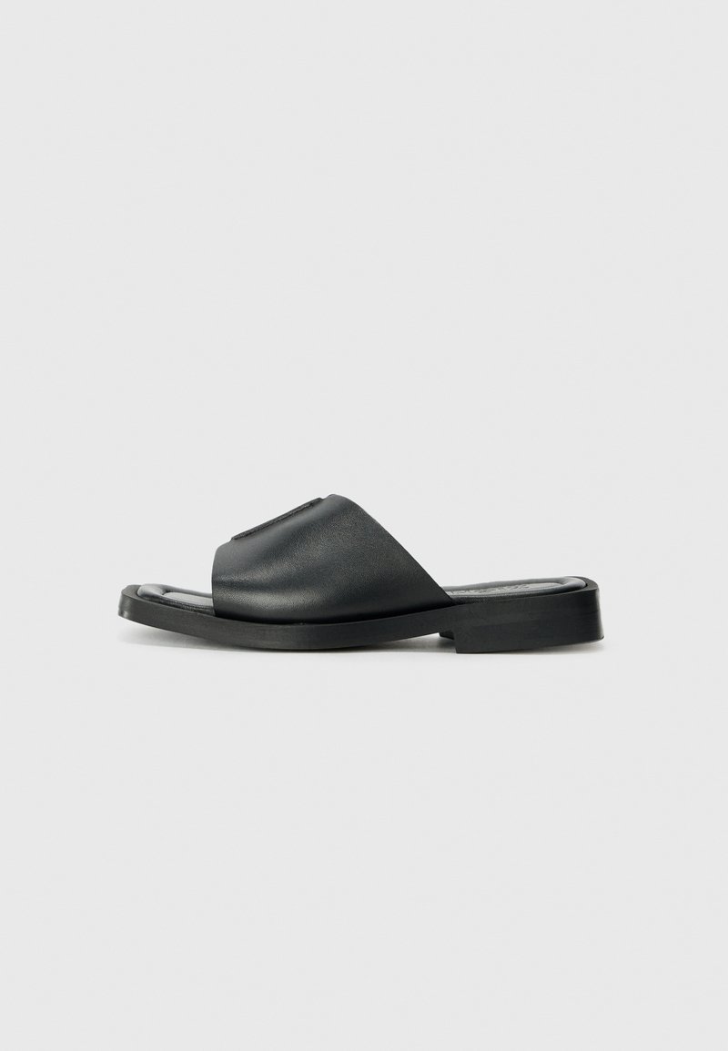 Black leather slide sandal with a smooth texture, open toe, wide strap design, and a flat rubber sole.