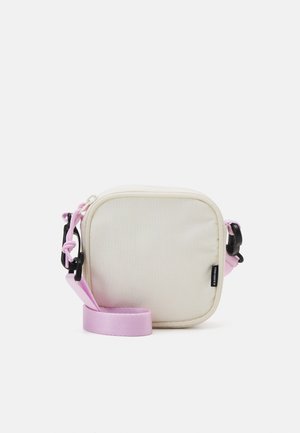 Bolso bandolera cuadrado pequeño en color crema con correa ajustable rosa y clips de plástico negro, con una pequeña etiqueta de marca negra.