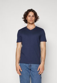 Navy blue v-neck t-shirt made of cotton. Short sleeves and a fitted shape. Smooth fabric texture with minimal design details.