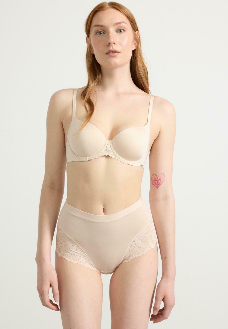 Beige alusharjoitus, jossa on pehmustettu rintaliivi pitsireunuksella ja korkeavyötäröiset alushousut, joissa on kukalliset pitsipaneelit. Sileä rakenne, minimalistinen muotoilu.