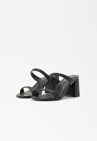Sandales noires à talons avec deux fines sangles, à bout ouvert, et un talon carré épais. Matériau en cuir lisse, design minimaliste.