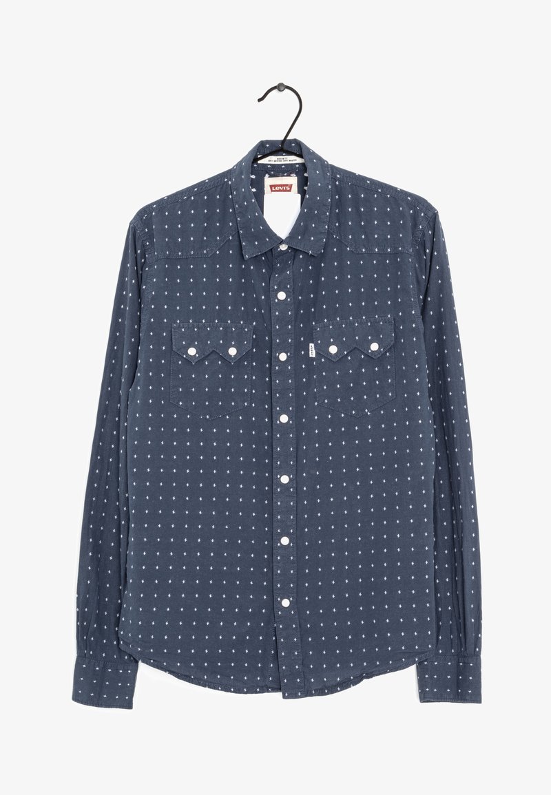 Chemise Levi's bleu marine à boutons avec motif à pois blancs, deux poches poitrine à rabat, présentée sur un cintre noir sur fond blanc.