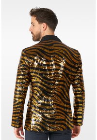 Schwarze und goldene Paillettenblazer mit wellenförmigen Mustern, einem schwarzen Kragen und taillierter Passform. Die Rückansicht hebt die funkelnde Textur und das Design hervor.