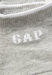 Calcetines de punto grises con un logo blanco de "GAP". La tela presenta una textura sutil con un puño acanalado y una construcción ligera.