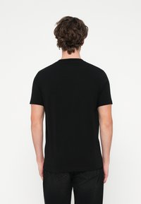 T-shirt preta de manga curta feita de algodão, com gola clássica redonda e corte descontraído, sem padrões ou detalhes visíveis.