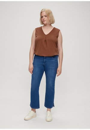 Top marrón sin mangas con escote en V y pliegue central, combinado con jeans rectos azules y zapatillas blancas. Diseño simple y moderno.