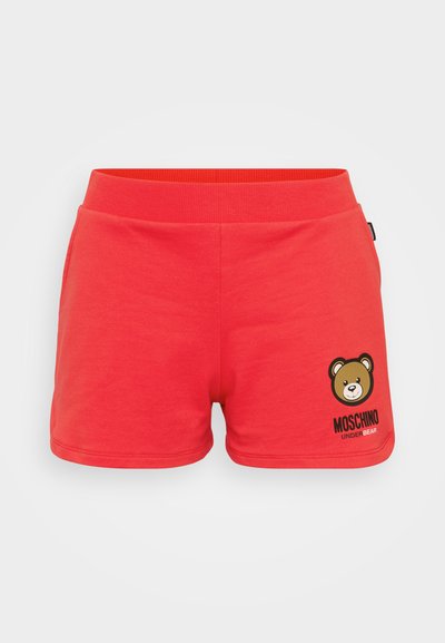 Pantaloni corti in cotone rosso con cintura elastica, caratterizzati da una grafica di un orso e il testo "Moschino Under Bear" sul fronte. Texture morbida.