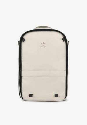 Zaino realizzato in tessuto beige chiaro con rifiniture nere. Presenta un logo sul davanti, una tasca con zip e spallacci regolabili.