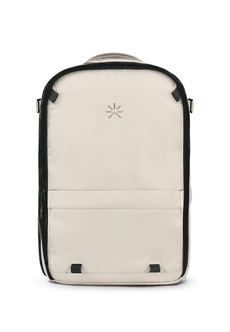 Mochila hecha de tela beige clara con un ribete negro. Presenta un logo en la parte frontal, un bolsillo con cremallera y correas ajustables.