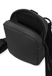 Borsa a tracolla nera con superficie liscia e opaca, forma arrotondata e chiusura con zip. Presenta un interno strutturato e una tracolla regolabile.