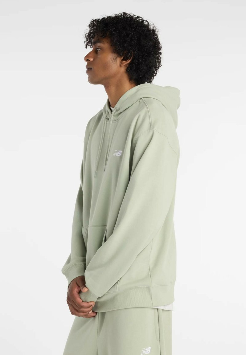 Hellgrüner Hoodie aus weichem Material, mit einer Kängurutasche, einer Kapuze mit Kordelzug und Logodetail auf der Brust. Lange Ärmel.