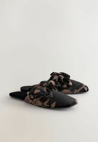 Schwarze Hausschuhe mit floralen Mustern in Kupfer, ausgestattet mit einer Schleifenverzierung. Hergestellt aus weichem Stoff mit einem spitzen Design und flacher Sohle.