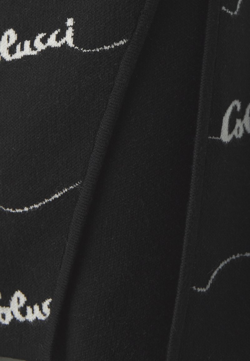 Schwarzer Strickstoff mit weißem Schriftzug, der "Colucci" spell. Die Textur wirkt weich mit sichtbaren Nähten.