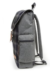 Ryggsäck i grått tyg med en rutmönstrad ficka. Har en zip-ficka på sidan, justerbara remmar och ett handtag på toppen.