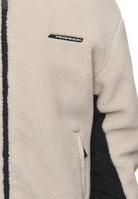 Giacca in fleece con un corpo bianco crema, dettagli neri, chiusura con zip e un piccolo logo nero sul petto. Tessuto morbido e strutturato.