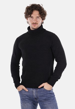 Maglione nero a collo alto caratterizzato da una texture a coste, maniche lunghe e un design aderente, indossato con jeans blu.